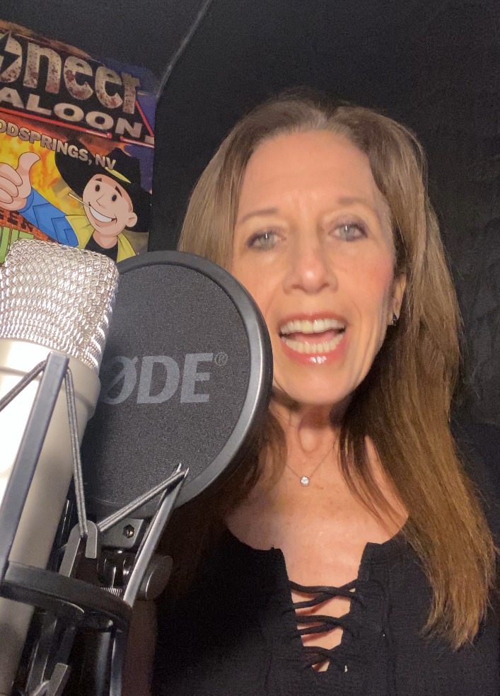 headshot of female voiceover artist Wendy Papier, Wendy is in her recording studio posing with her recoding mic